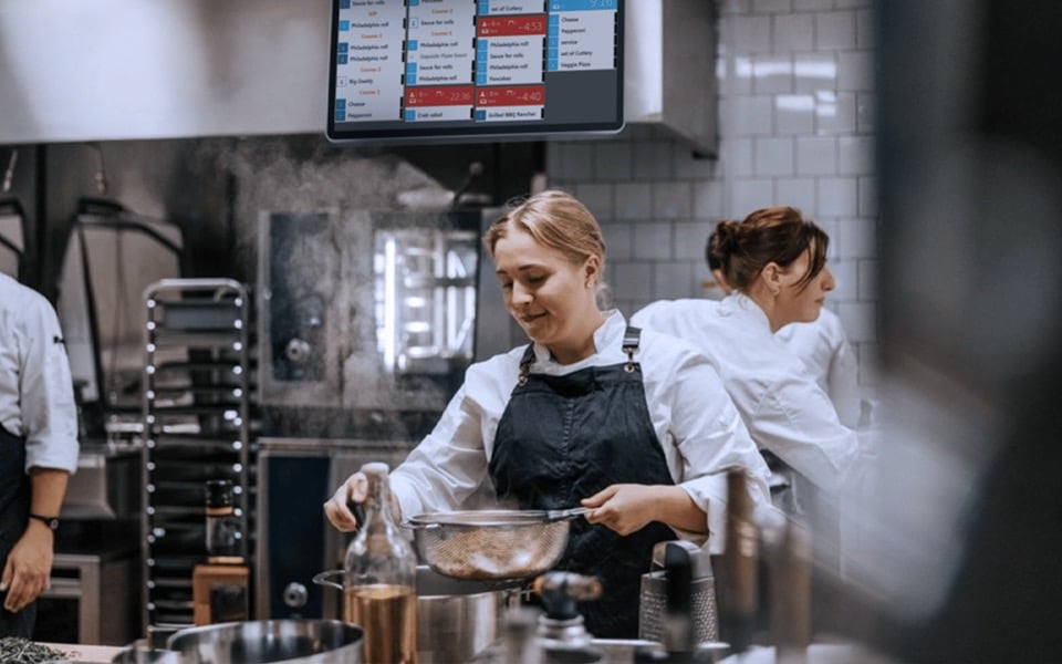Restaurant staff using automated order processing system to manage incoming orders efficiently