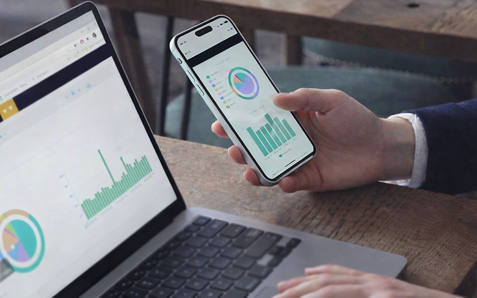 Restaurant owner analyzing sales data and performance insights on laptop and mobile