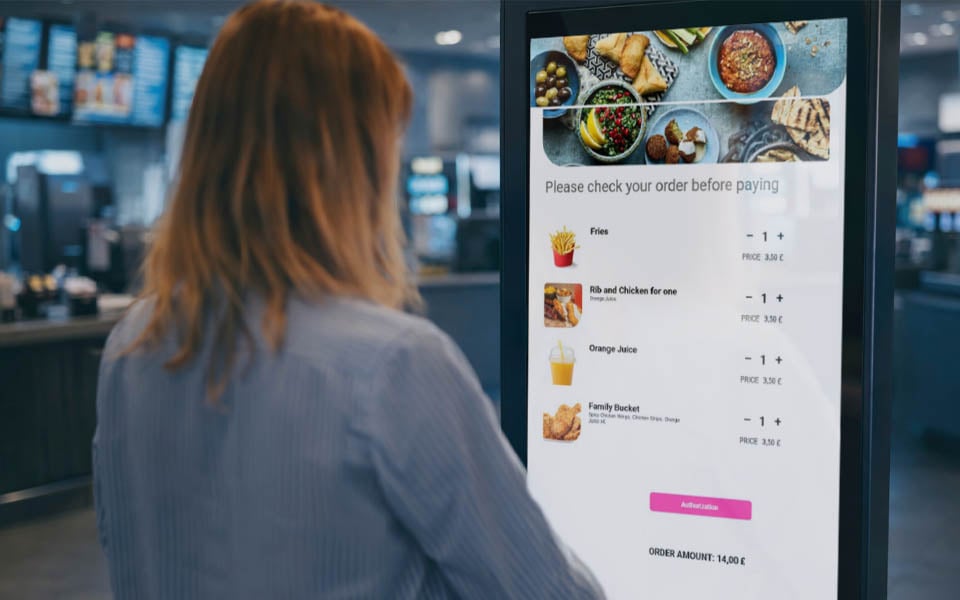 Customer reviewing order on self-service kiosk before payment