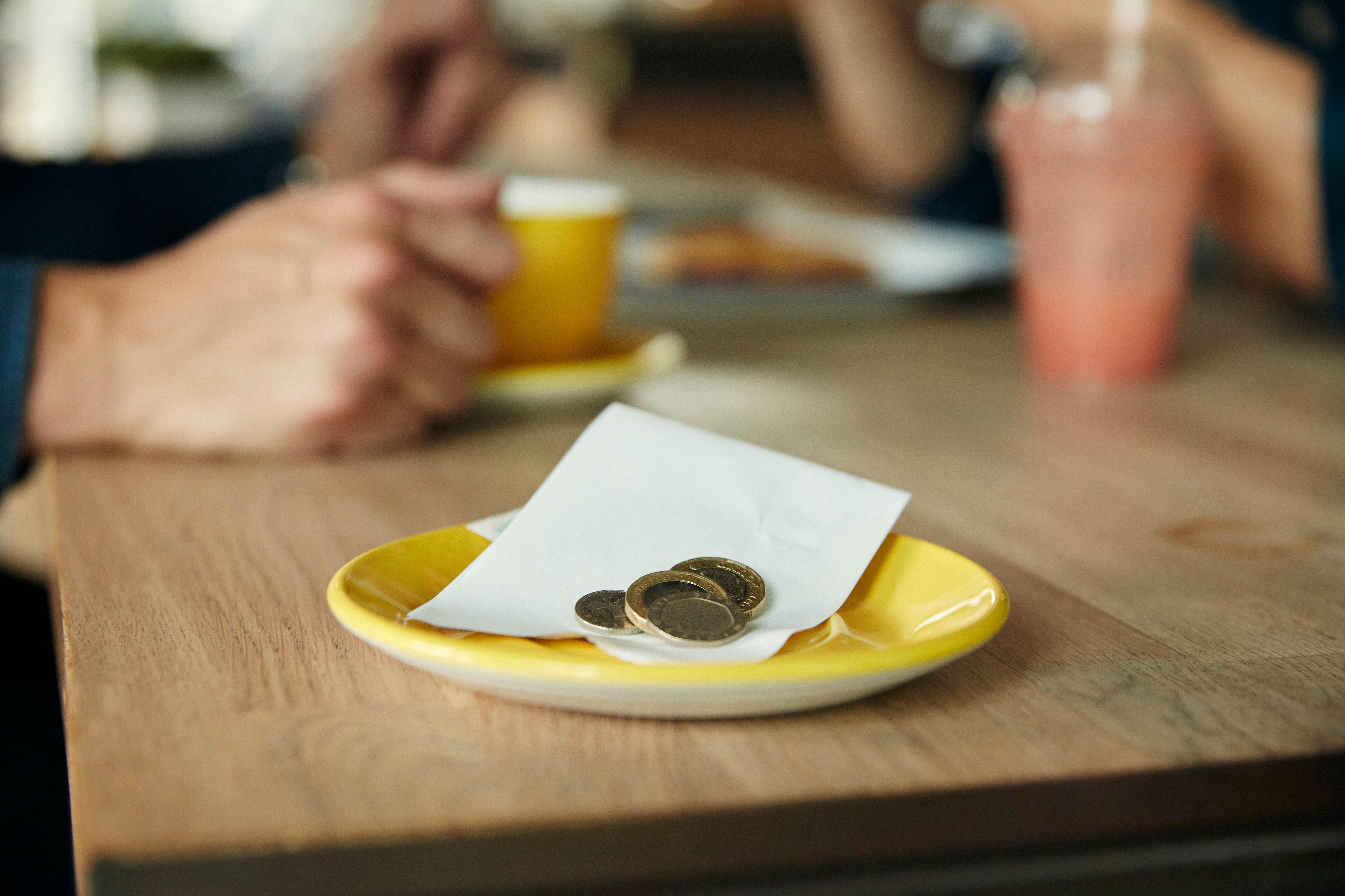 a-small-saucer-with-a-till-receipt-and-coins-cash-2023-11-27-05-25-20-utc