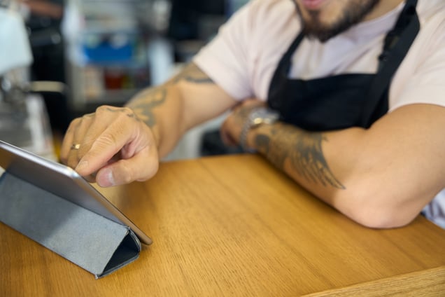 busy-coffee-shop-worker-using-tablet-to-calculate-2023-11-27-04-54-17-utc