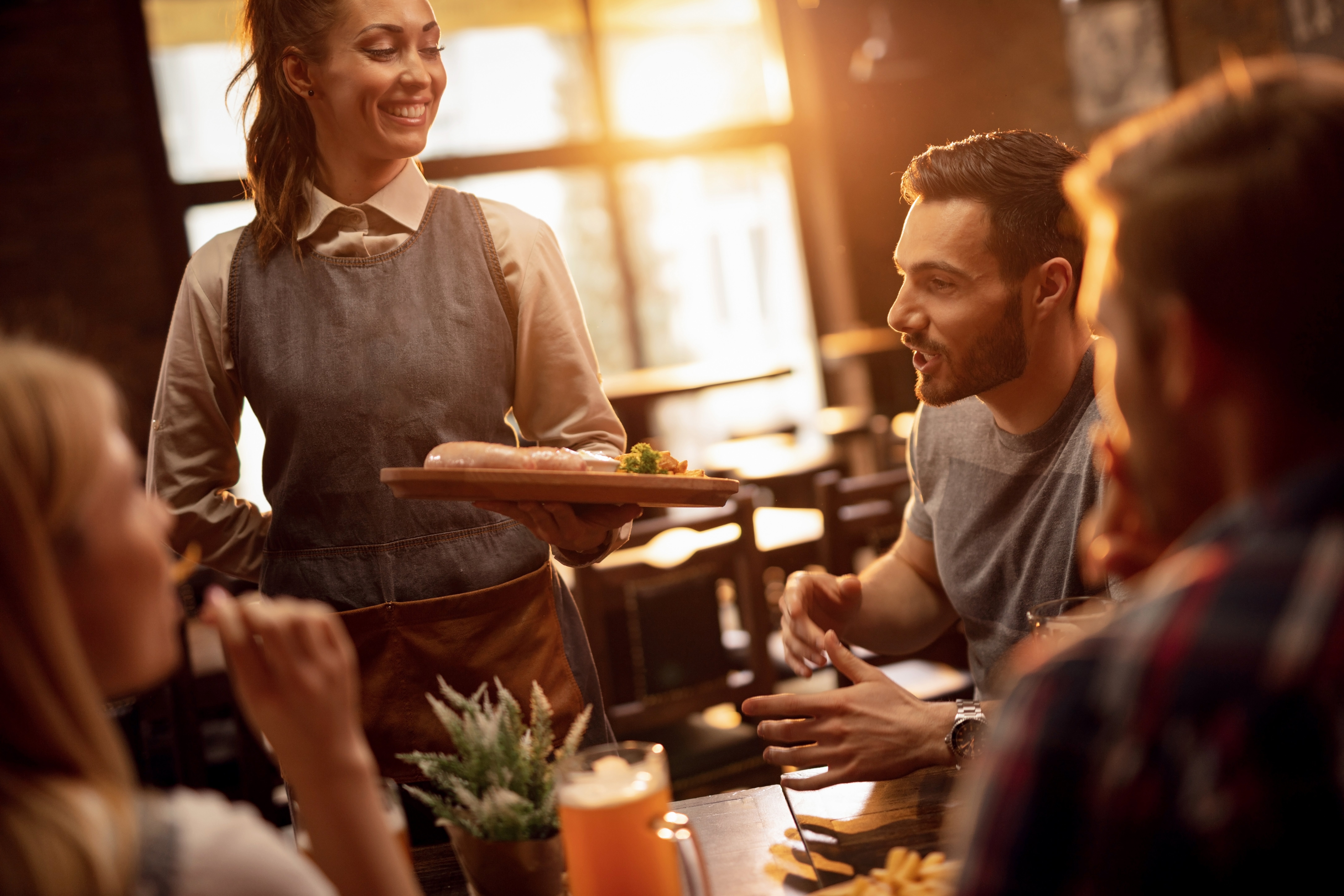 happy-waitress-serving-lunch-to-group-of-friends-i-2023-11-27-05-20-03-utc