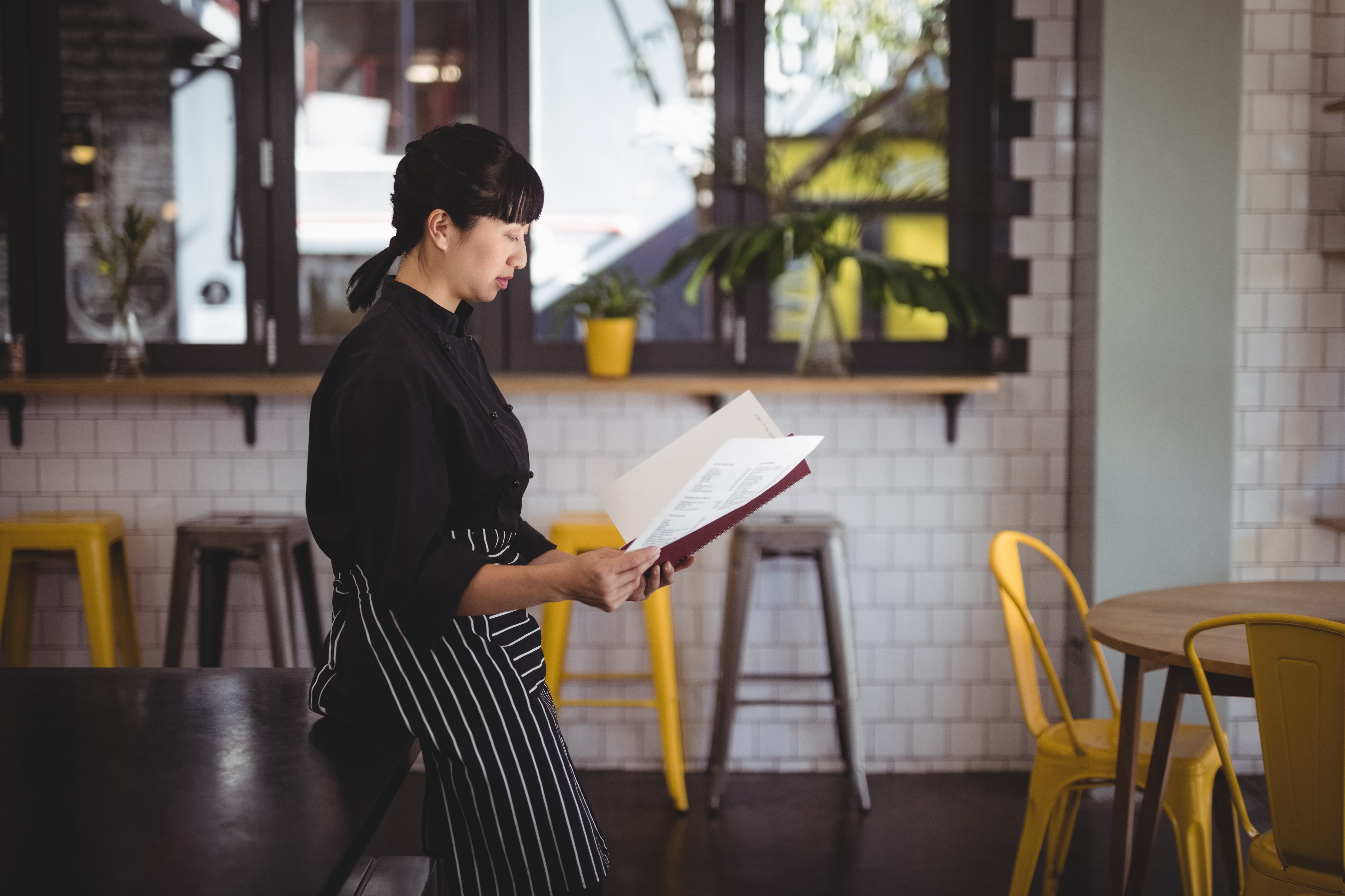 side-view-of-young-waitress-reading-menu-while-lea-2023-11-27-05-36-41-utc