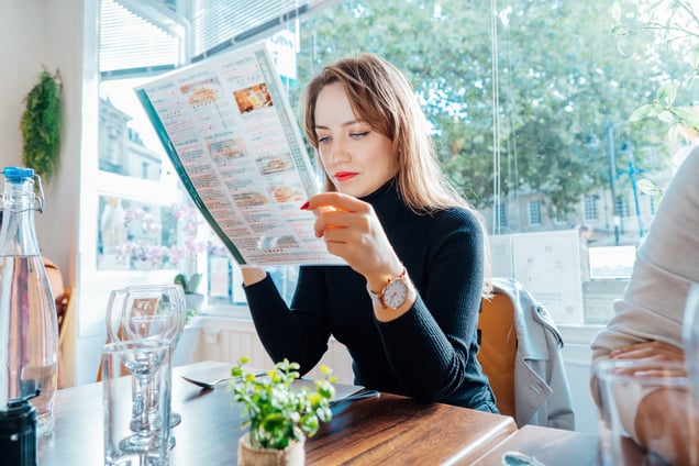 young-woman-reading-menu-sitting-with-friend-at-ca-2023-11-27-05-01-44-utc